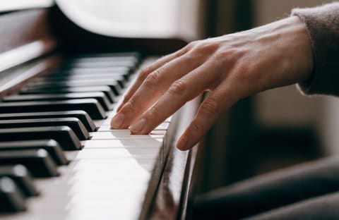 A hand on piano keys forming a chord in soft daylight